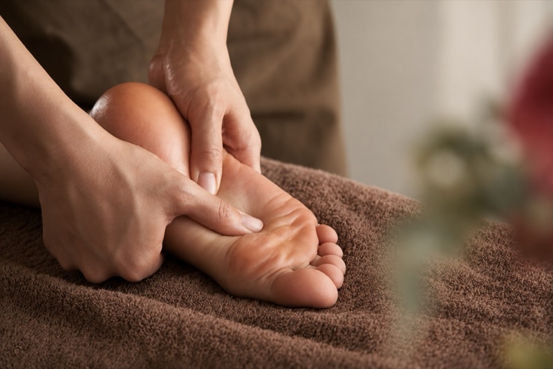 Oil foot care with both hands treating the soles