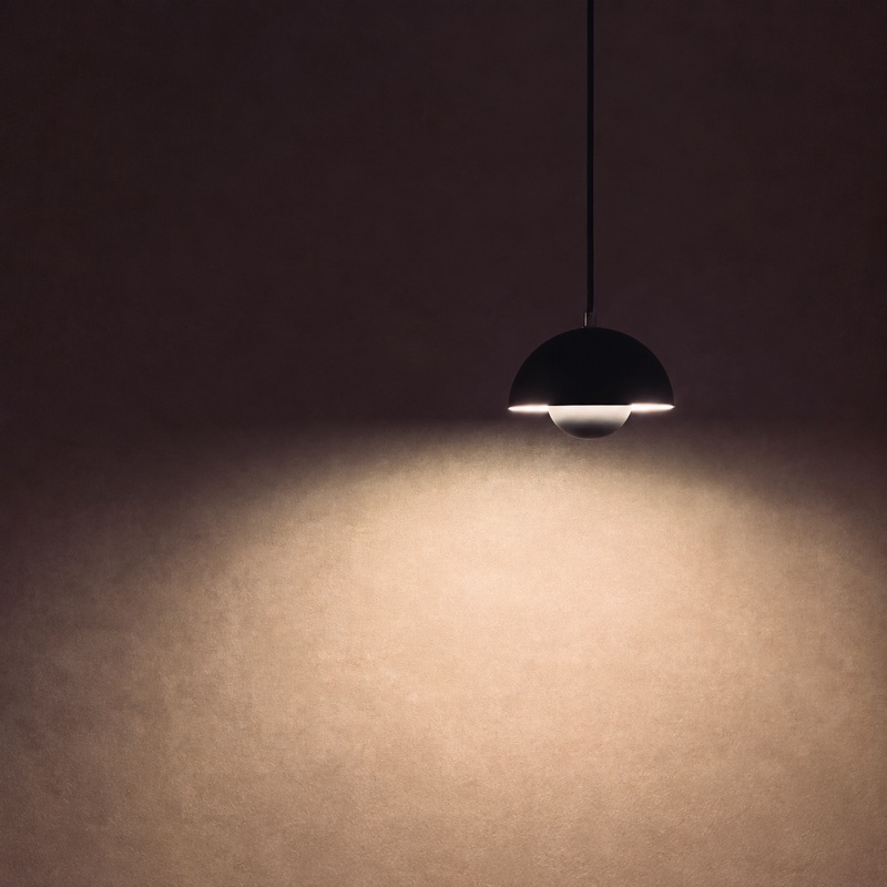 A black pendant casting warm light on the wall