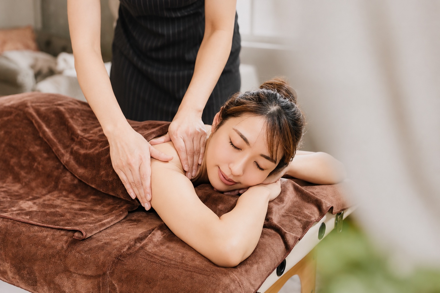 An aromatherapy treatment carefully tending to the shoulders of a guest lying face down
