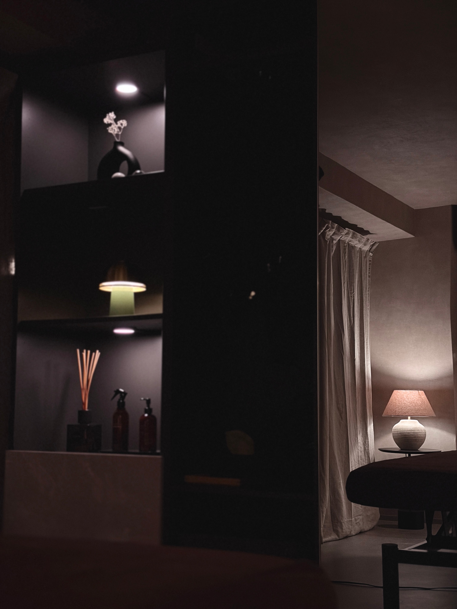 An illuminated display shelf with curtains and a private room behind it